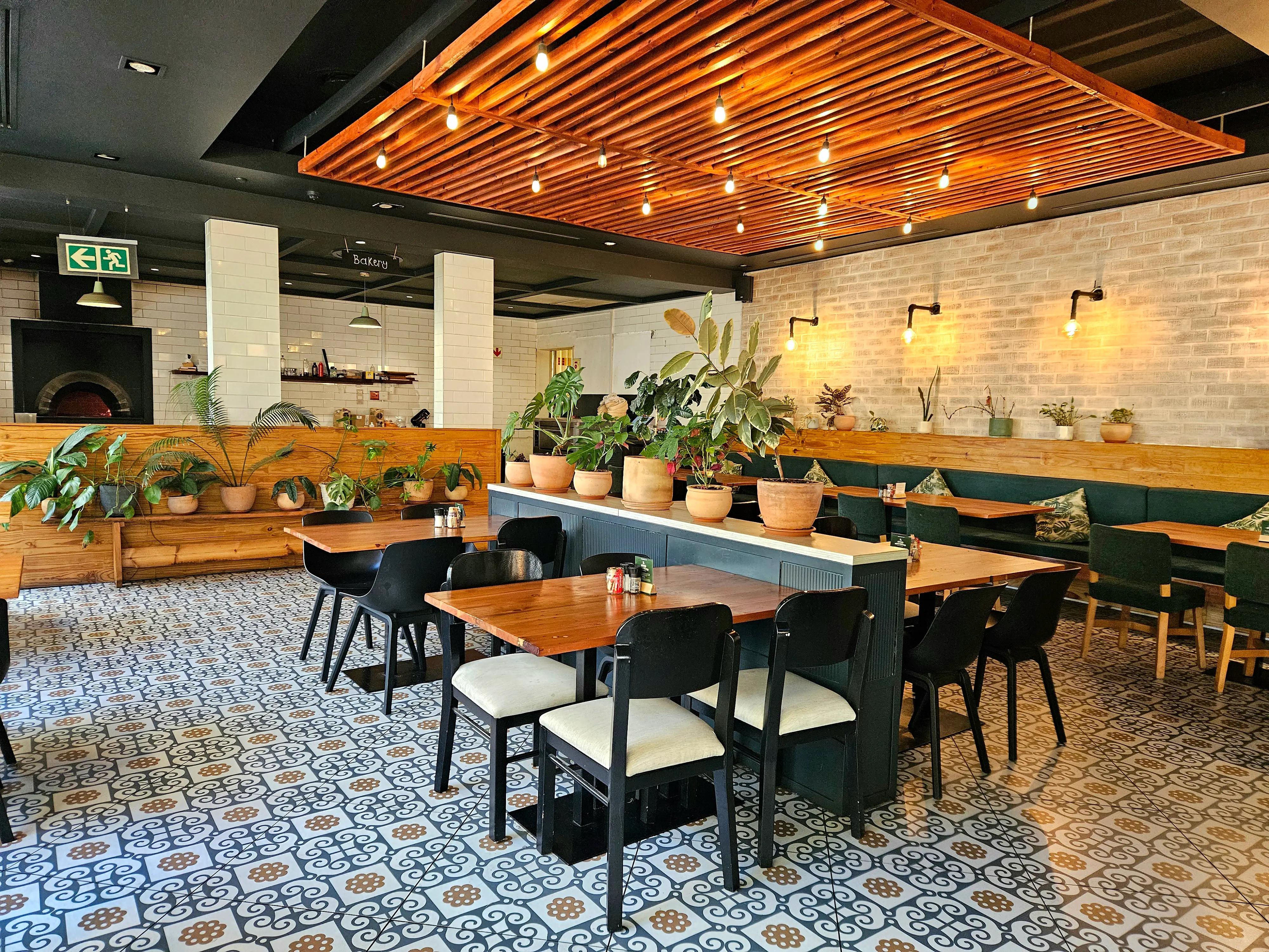Inside The Good Neighbour café — dining room with tiled floors, pendant lights and lush plants
